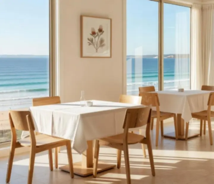 Ocean-view dining room with pale stone, white linens and coastal light at Lucky Pamppa